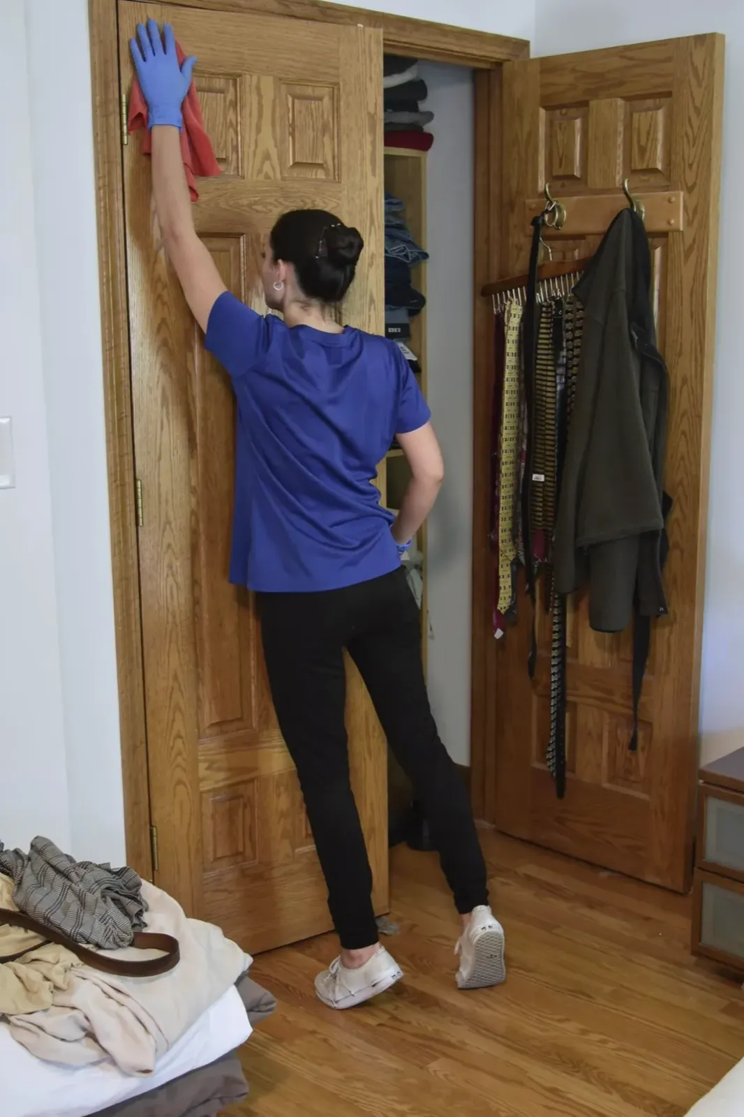 A Happy Maids technician hand-dusting the top of a door frame